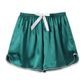 Detailed view of dark green satin sleep shorts with white bow and curved hem - Dark Green