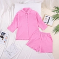 Detail van roze katoenen mousseline loungewear set met shirt en korte broek op het bed - Roze