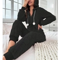 Détail d'un pyjama en polaire noire avec texture quadrillée et pompons blancs décoratifs - Noir