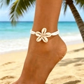 Bohemian white beaded anklet with natural cowrie shell flower detail on sunny beach - White Shell Star Flower Style (5563) / 【product Attributes】bohemian Style Anklet Made Of Double Rows Of White Micro-beads With A Central Star Pattern Composed Of Five Natural Beige Conch Shells. 【visual Presentation】the Image Is A Real Person Wearing The Anklet Taken On A Tropical Beach. The Background Shows Clear Seawater White Sand And Palm Leaves With A Sunny And Natural Tone. Image Quality Is [high] Sharp Focus And Excellent Detail. Aesthetic Appeal Is [high] Overall Score Is [9.0] The Scene And Product Theme Are Highly Compatible Conveying A Vacation Feel And Brand Aesthetics. 【text Content】no Superimposed Text Or Watermarks In The Image. 【logistics Labels】none. 【infringement Risk】product Infringement: None; Background Infringement: None. 【product Parameters】white Beads Natural Shell Material Elastic Design.