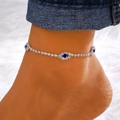 Silver evil eye anklet with sparkling blue rhinestones worn against denim fabric - Silver Rhinestone Flower & Blue Eye Style (Eye # Silver 7490)
