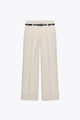 Dettaglio dei pantaloni a gamba larga crema con pieghe frontali e cintura nera sottile - XS / Beige