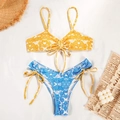 Flat lay of floral bikini with yellow top and blue bottoms on summer resort background - S