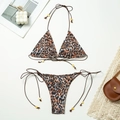 Flat lay of leopard print bikini set with neck ties and decorative gold beads - Leopard Print