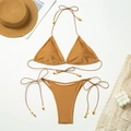 Flat lay of caramel bikini set with tie-sides and golden bead accents on white background - Gold
