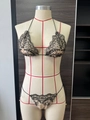 Detailopname van beige bikiniset met zwart bloemenkant borduursel en strikjes aan de zijkant - S / Zwart