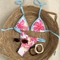 Dettaglio ravvicinato del bikini floreale in un cesto con accessori estivi alla moda - S / Blu