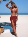 Detail of red textured knit bikini top and high-slit sarong skirt with pom-poms on a beach - Red