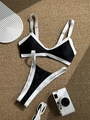 Bikini bicolore noir et blanc posé sur une natte en paille avec accessoires de plage - S / Noir