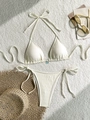 Dettaglio bikini color crema testurizzato con ciondolo a fiore blu su tappeto - S / Beige