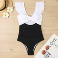 Flat lay view of a color block one piece swimsuit with ruffle straps on wood background - S / White + Black