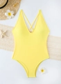 Flat lay of bright yellow one-piece swimsuit with V-neck and beach vacation accessories - S / Yellow