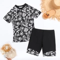 Flat lay of tropical floral two-piece swimsuit with zipper top and black swim shorts - S / White Leaf