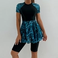 Detail of short-sleeved surf swimsuit featuring black bodice and teal floral ruffle skirt - S / Black