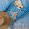 Detail der silbernen Metallic-Bikinihose mit Seitenschnallen auf Strand-Accessoires - Grau
