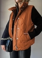 Detail of autumn quilted vest in burnt orange featuring a high neck and silver buttons - Caramel color