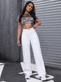 Dettaglio di jeans bianchi a vita alta a gamba larga con crop top grafico vintage - Bianco