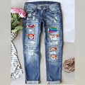 Blaue Jeans mit Rissen und weihnachtlichen Weihnachtsmann- und Regenbogen-Patches - S / Waschblau Weihnachtsdruck