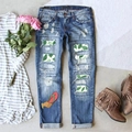 Distressed blue straight jeans with floral leaf patches and ripped details on wood surface - Flip Flop Style (TP2404135)