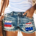 Dettaglio di pantaloncini in denim consumati con toppe bandiera USA e orli sfilacciati - S / Azzurro