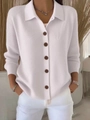 Detail of white knit cardigan showing five brown buttons and a classic polo collar design - White