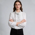 Detail van de ruffelhals en decoratieve bloemaccent op dit witte polkadot damesoverhemd - S / Wit