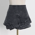 Dettaglio di gonna-pantalone in denim lavaggio acido nero con vita asimmetrica a strati - S / Nero