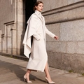Detailed view of cream white trench coat featuring a layered cape and refined minimalist cut - S / Apricot
