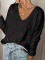 Detailed close-up of a women's V-neck sweater featuring red heart patterns on black knit - S / Black