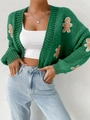 Close-up of green knit cardigan featuring gingerbread man patches and thick knit texture - Green