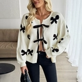 Cream knit cardigan for women featuring black bow patterns and satin ribbon ties - S / Off White