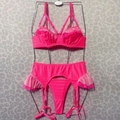 Driedelige neonroze lingerieset met ruches en jarretelgordel op een kledinghanger - S / Neonroze