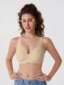 Detalle de un sujetador beige sin costuras con escote en V profundo en una modelo - S / Color Piel