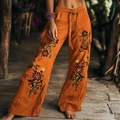 Detail van een bohemien oranje linnen broek met bloemenborduursels en trekkoord in de taille - Oranjerood