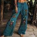 Detail van bloemenprints en zijzak op wijde bohemien broek in diepblauwe kleur - Pauwgroen