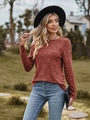 Detail van roestrode gebreide top met lange mouwen, ribstructuur en blauwe jeans - S / Baksteenrood