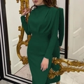 Detail of dark green slim-fit dress with high neck and waist gathering in front of gold mirror - Green