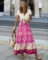 Detail eines Boho-Maxirocks mit Blumendruck, Rüschensaum und weißem V-Ausschnitt-Oberteil - Fuchsia