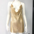 Detail van gouden pailletten mini-jurk met gedrapeerde halslijn en metalen kettingen - S / Goud