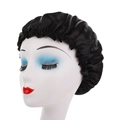 Detail view of black satin sleep cap with elastic ruffled edge on a white mannequin head - Black