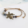 Handgewebtes Keramik-Perlenarmband mit Bronze-Schmetterlingsanhänger und blauer Glasur - Blumenglasur Juwelenblau