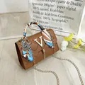 Brown quilted crossbody bag with golden V-hardware, tassel detail and silk scarf handle - Brown