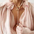 Elegant pearl necklace with golden rings worn on a model with a soft pink chiffon blouse - Necklace