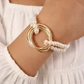 Elegant double-layer pearl bracelet with interlocking gold rings on a model wrist - Bracelet