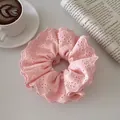 Détail d'un chouchou en dentelle rose avec broderie florale et froufrous étagés - Style à Volants en Dentelle / Rose