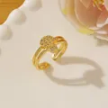 Close-up of gold Hamsa ring with white zircons on a minimalist white ceramic plate - Adjustable Open / Gold Hamsa Hand Micro-set Style (Q)