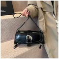 Detail of glossy black leather underarm bag featuring irregular silver buckle and zippers - Black