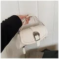 Close-up of white leather shoulder bag featuring a large silver buckle and zipper details - White