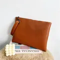 Oranjebruine envelopclutch met krokodillenreliëf en polsband op houten standaard - Geelbruin