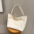 Minimalist off-white canvas tote bag with front pocket on a wooden stool - Beige